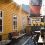 Sonniger Innenhof mit gelbem Gebäude, Grill und Holzmöbeln.