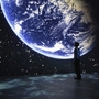 Person betrachtet Projektion des Planeten Erde in einem dunklen Raum.
