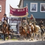 Reiter in Westernkleidung mit Banner in einer Westernstadt.