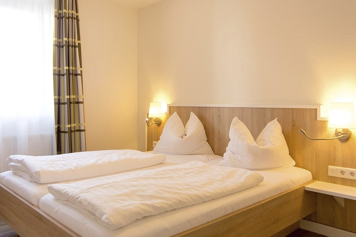 Helles Schlafzimmer mit Doppelbett und Nachttischlampen in der Ferienanlage Braunlage.