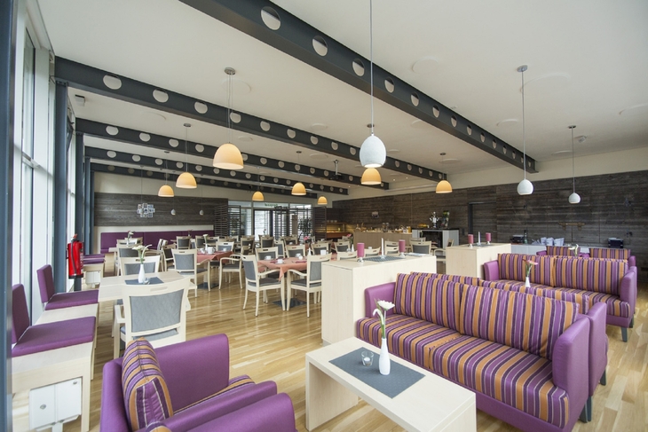 Moderner Speisesaal mit bunten Sofas und Tischen im Bergsaal in Ferienanlage Braunlage.