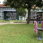 Spielplatz mit Wipptier und Spielturm auf einer Wiese vor einem Gebäude der Ferienanlage Braunlage.