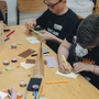 Kinder basteln an einem Tisch mit Papier und Stiften.