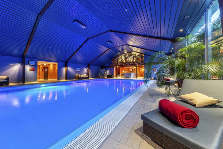 Innenansicht eines Schwimmbads im Eurostrand Resort mit Liegen und Palmen.