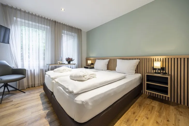 Modernes Hotelzimmer mit Doppelbett und Fenster im Eurostrand Resort Fintel.