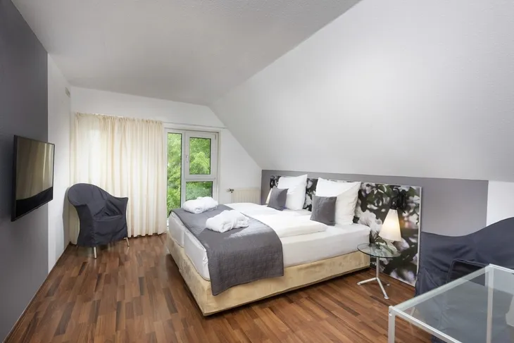 Modernes Schlafzimmer mit Doppelbett, zwei Sesseln und großen Fenstern im Eurostrand Resort.
