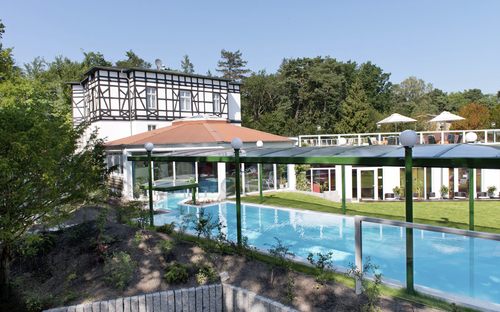 Außenansicht des Ostseehotels Waldschlösschen mit Pool und Garten bei Tageslicht.