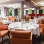 Restaurant mit gedeckten Tischen und orangen Stühlen im Ostseehotel Waldschlösschen.