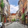 Schmale Straße in Brüssel mit bunten Gebäuden und Fußgängern.