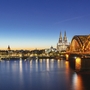 Kölner Dom und beleuchtete Hohenzollernbrücke bei Nacht.