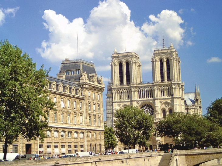 Gebäudeansicht mit Notre-Dame-Kathedrale und blauem Himmel im Hintergrund.