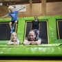 Familie springt auf Trampolinen in einer Indoor-Freizeithalle.