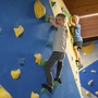 Kinder klettern in einer Indoor-Kletterhalle auf bunten Klettergriffen.