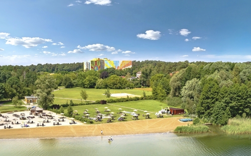 Außenansicht Ahorn Seehotel Templin im Sommer mit Strand und grüner Umgebung.