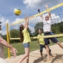 Leute spielen Beachvolleyball im Freien bei sonnigem Wetter.