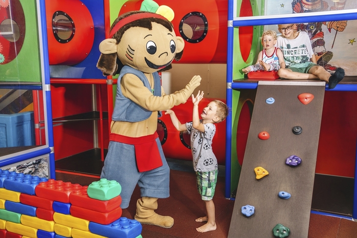 Maskottchen spielt mit Kindern im Indoor-Spielbereich des Ahorn Seehotel Templin.