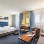Helles Hotelzimmer mit Doppelbett, Schreibtisch und Seeblick in Templin.