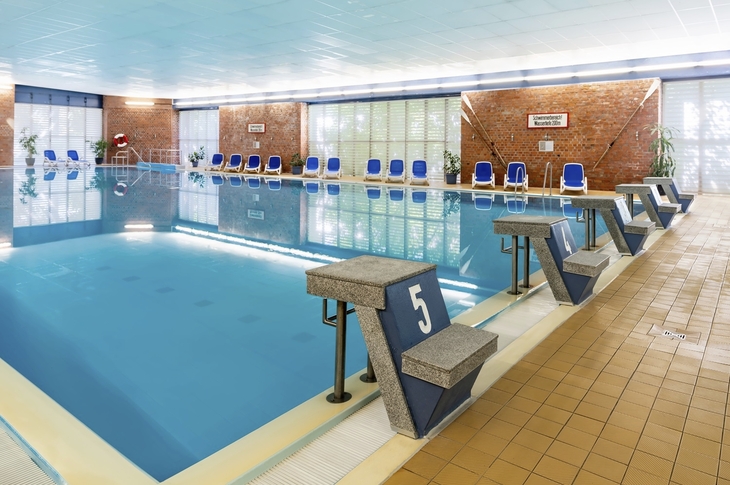 Hotel-Innenpool mit blauen Stühlen und Startblöcken am Beckenrand