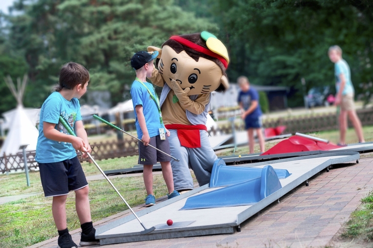 Kinder spielen mit Minigolfschlägern im Freien.