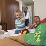Mann, Kind und Frau spielen lächelnd in einem Familienzimmer.