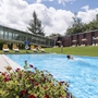 Außenpool des Waldhotels Altenberg, ein Schwimmer im Wasser, Liegestühle am Beckenrand.