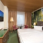 Hotelzimmer mit Doppelbett, Waldmotiv an der Wand und Flachbild-TV.