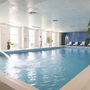 Innenpool im Ahorn Waldhotel Altenberg mit Liegestühlen und Pflanzen.