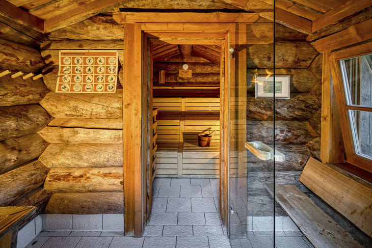 Eingang zu einer Sauna aus Holz mit Fenster und Sitzbank im Hotel Rhön Garden.