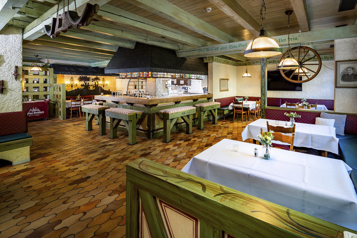 Rustikal eingerichtetes Restaurant mit Holzmöbeln und gedeckten Tischen.