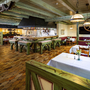 Rustikal eingerichtetes Restaurant mit Holzmöbeln und gedeckten Tischen.