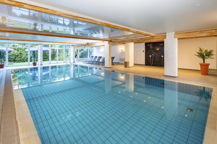 Innenpool mit Liegestühlen und Glasfronten im Hotel Rhön Garden in Poppenhausen