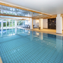 Innenpool mit Liegestühlen und Glasfronten im Hotel Rhön Garden in Poppenhausen