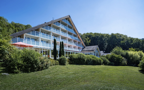 Hotelgebäude umgeben von Grünflächen und Bäumen bei klarem Himmel