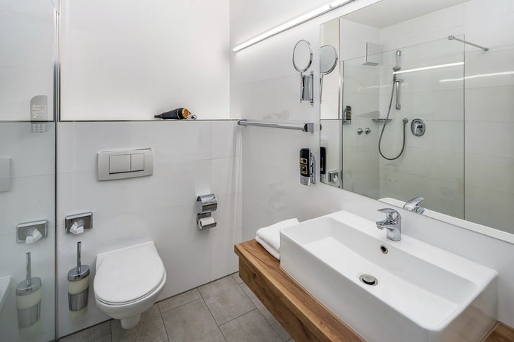 Modernes Hotelbad mit Duschkabine, Waschbecken und Toilette.