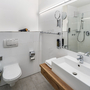 Modernes Hotelbad mit Duschkabine, Waschbecken und Toilette.