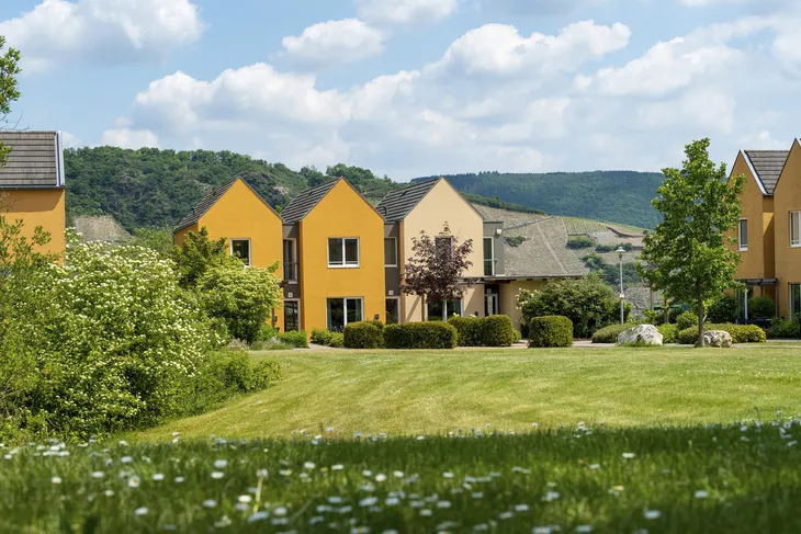 Außenansicht des Leiwen Eurostrand Resorts im Moseltal mit grüner Wiese und Gebäuden.