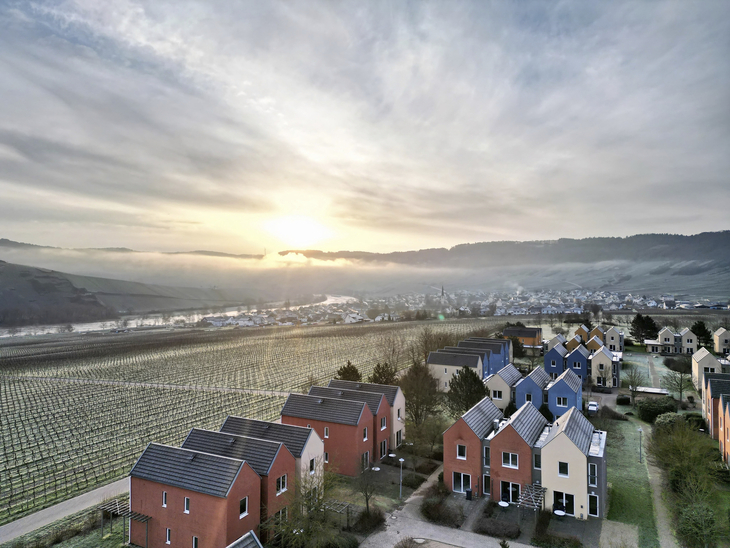 Winterliche Landschaft mit modernen Häusern und Weinbergen bei Sonnenaufgang im Moseltal.