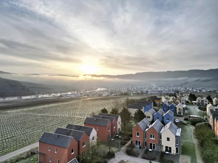 Winterliche Landschaft mit modernen Häusern und Weinbergen bei Sonnenaufgang im Moseltal.
