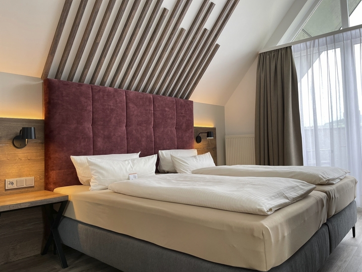 Doppelzimmer mit modernem Kopfteil und Fenster im Hotel Mainpromenade Karlstadt.