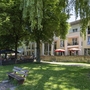 Hotel mit Biergarten und Bäumen außen bei Sonnenschein.