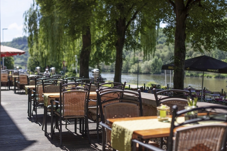 Außenterrasse des Karlstadt Hotels mit Blick auf den Fluss und Bäume im Hintergrund.