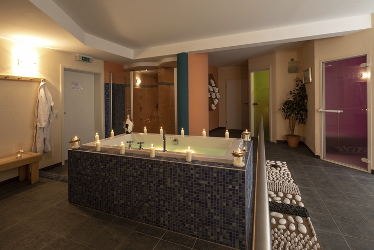 Wellnessbereich mit Whirlpool, Kerzen und moderner Einrichtung