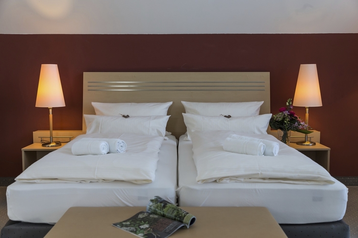 Hotelzimmer mit zwei Einzelbetten, Nachttischen und Stehlampen.