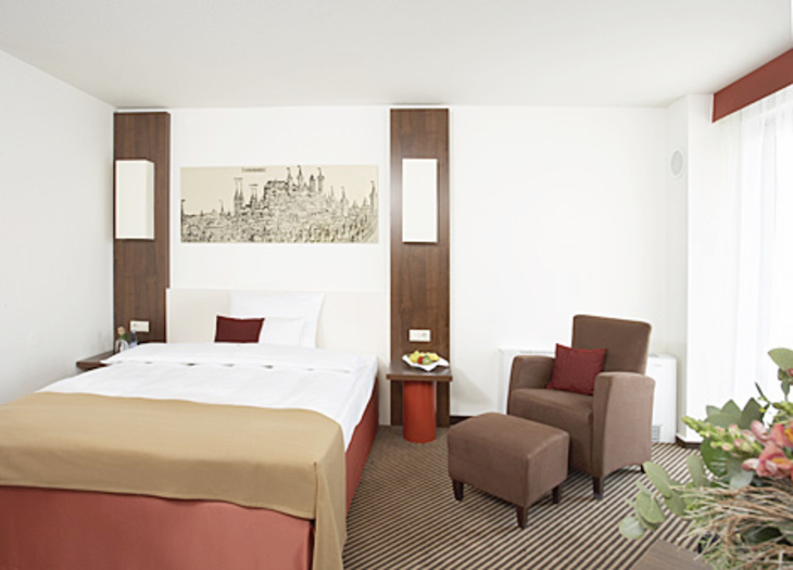 Zimmer im Best Western Hotel Nürnberg City West mit Doppelbett und Sitzbereich.