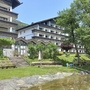 Appartementanlage am See mit Garten und Bäumen an einem sonnigen Tag.
