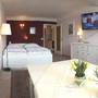Helles Apartmentzimmer mit Doppelbett, Esstisch, TV und Dekoration.