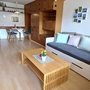 Wohnzimmer eines Apartments mit Sofa, Couchtisch und Essbereich im Hintergrund.