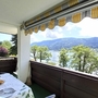 Balkon mit Tisch und Aussicht auf See und Berge bei sonnigem Wetter