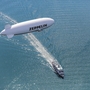 Zeppelin fliegt über Luftschiff und Boot auf offenem Wasser.