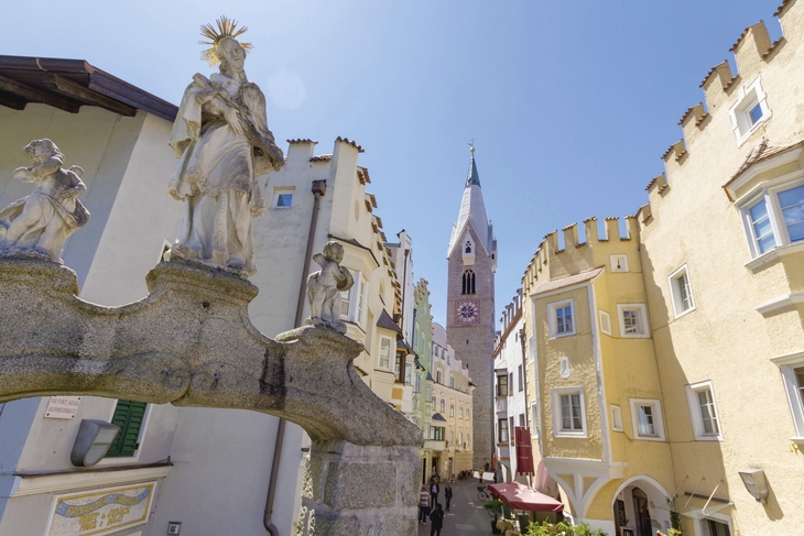 Historische Altstadt von Brixen mit Skulpturen und Kirchturm.